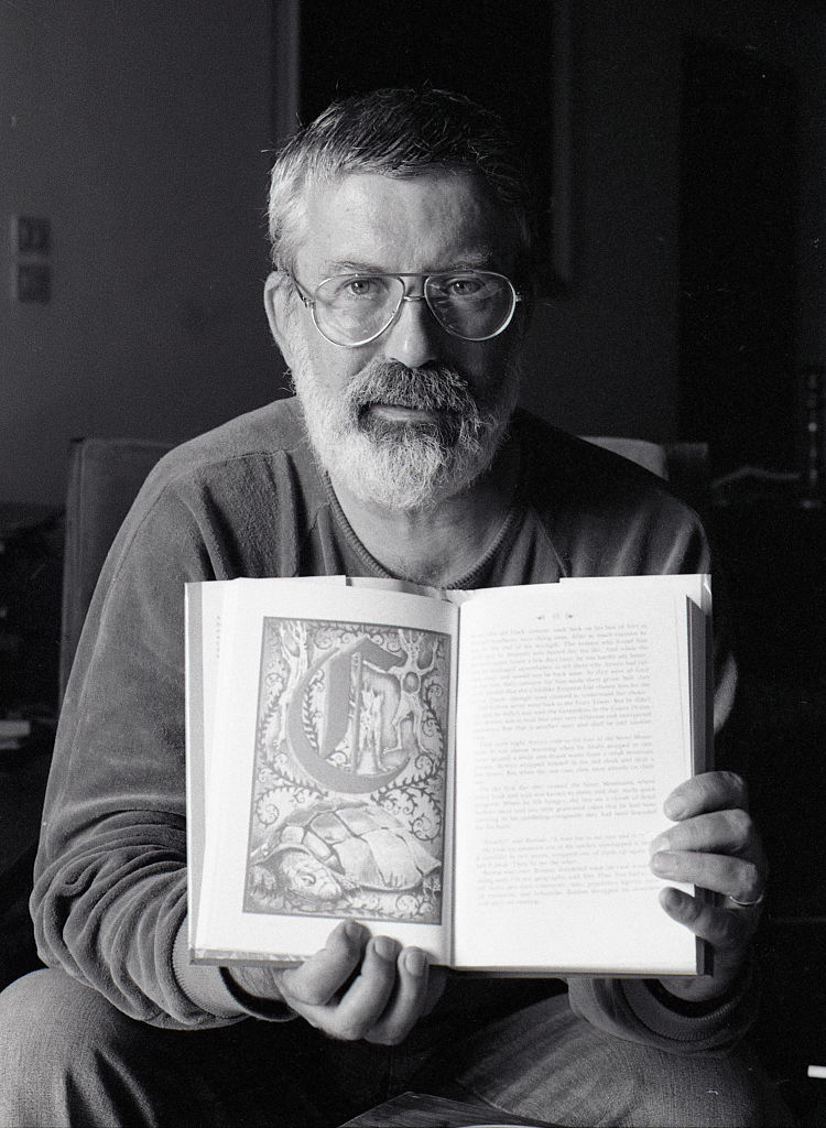 fotografía de michael ende en blanco y negro sujetando un ejemplar de 'La historia interminable' abierto en las manos, que muestra a cámara